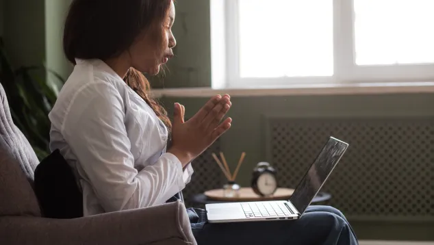 Woman in white coat communicating virtually on laptop
