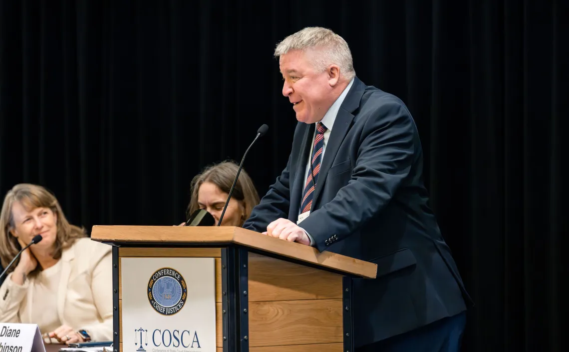 Man speaking at COSCA Conference of State Court Administrators podium.