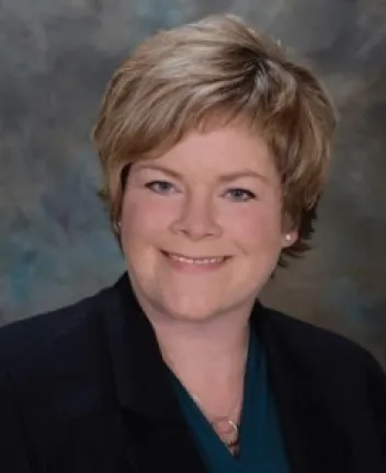 Professional headshot of a smiling woman in blazer.