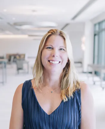 Smiling woman in navy blue dress with light background