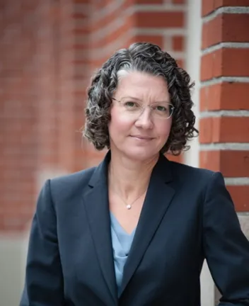 Professional woman in blazer standing by brick wall